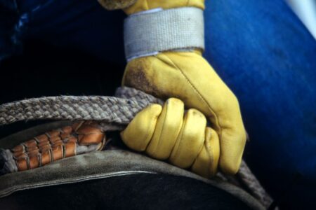 closeup cowboygloved hand gripping rope